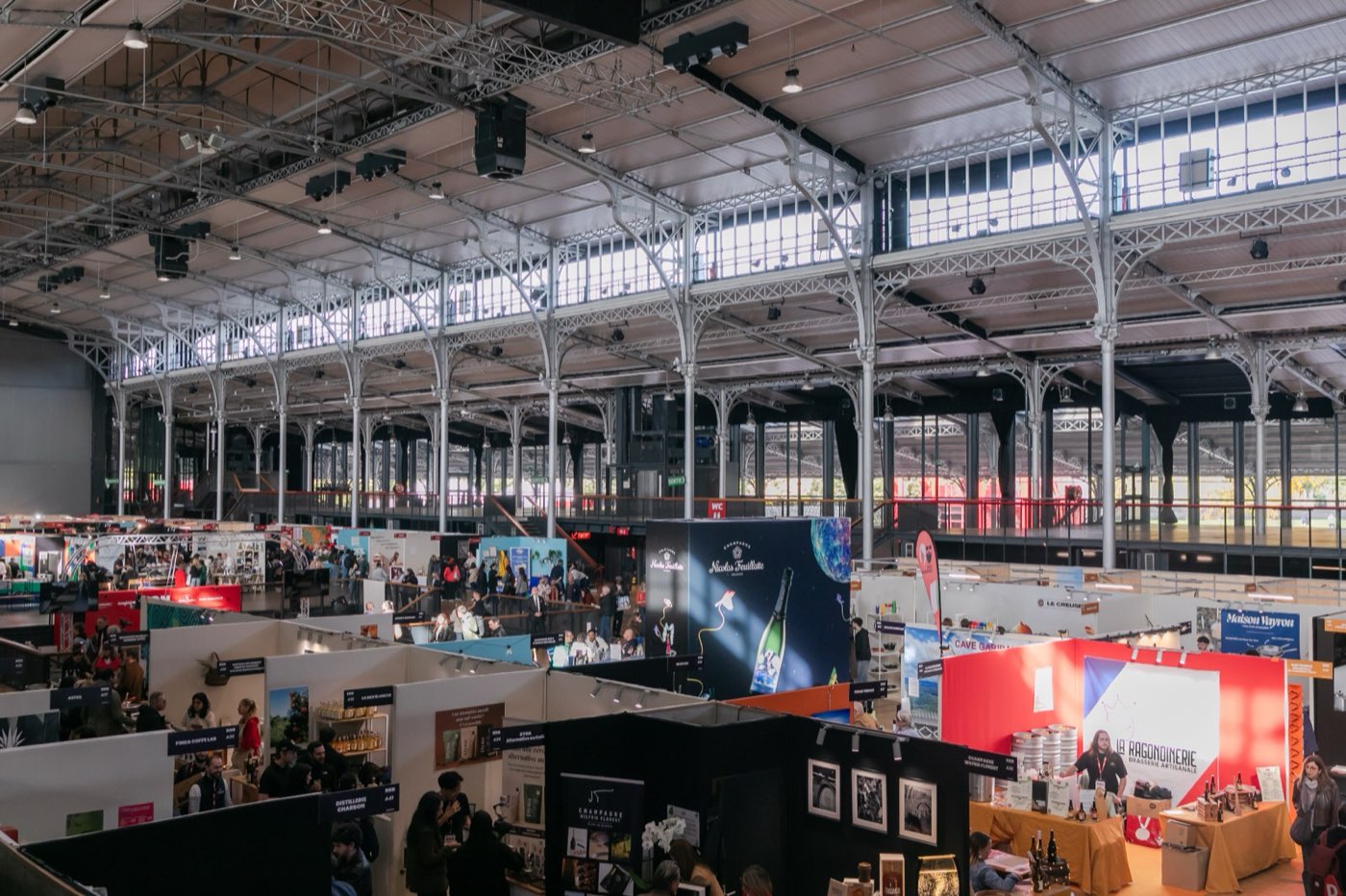 Vue d'ensemble des stands sous la charpente de la Grande Halle